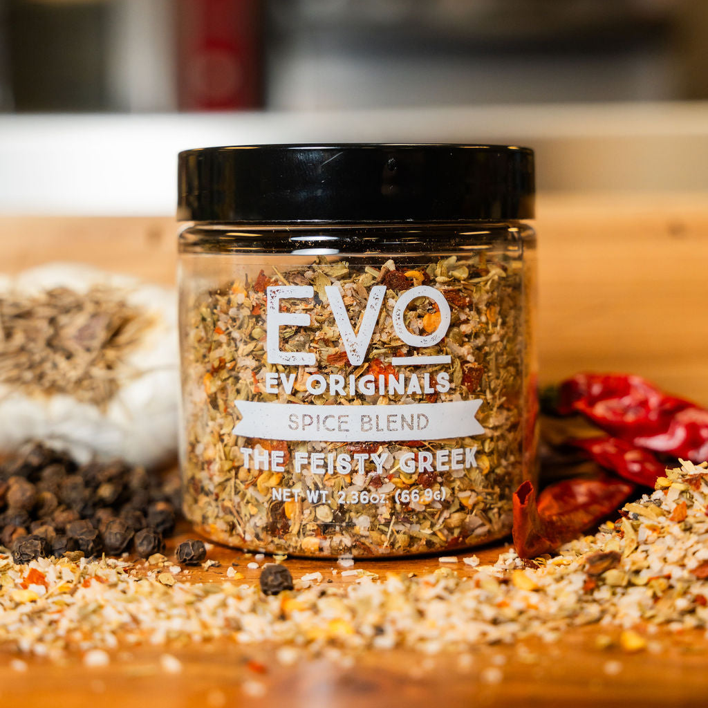 Jar of EVO Originals Spice Blend on a wooden surface with spices around